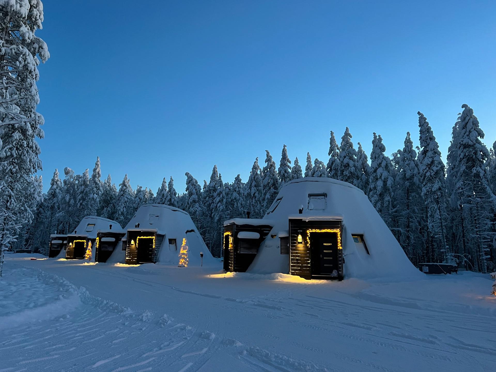 Snow covered cottages at Glass resort in Saariselka, Finland. Arriving in Santa Claus Village