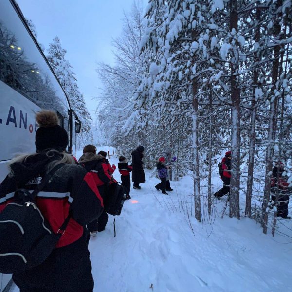 People getting out of the bus and walking in the snow in Rovaniemi, Finland. Christmas Day in Lapland