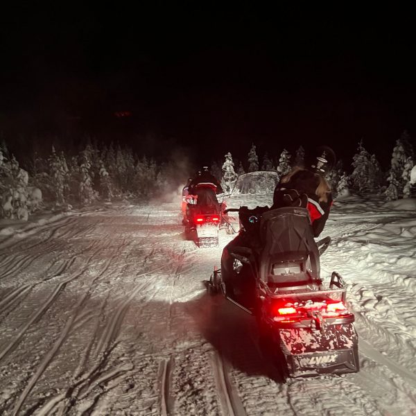 People riding snow mobiles at night in Rovaniemi, Finland. Christmas Day in Lapland
