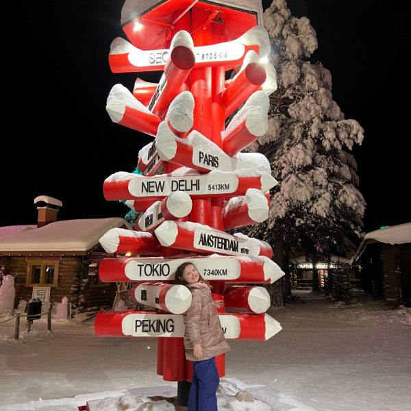 Niece and direction sign in Rovaniemi, Finland. Christmas Day in Lapland