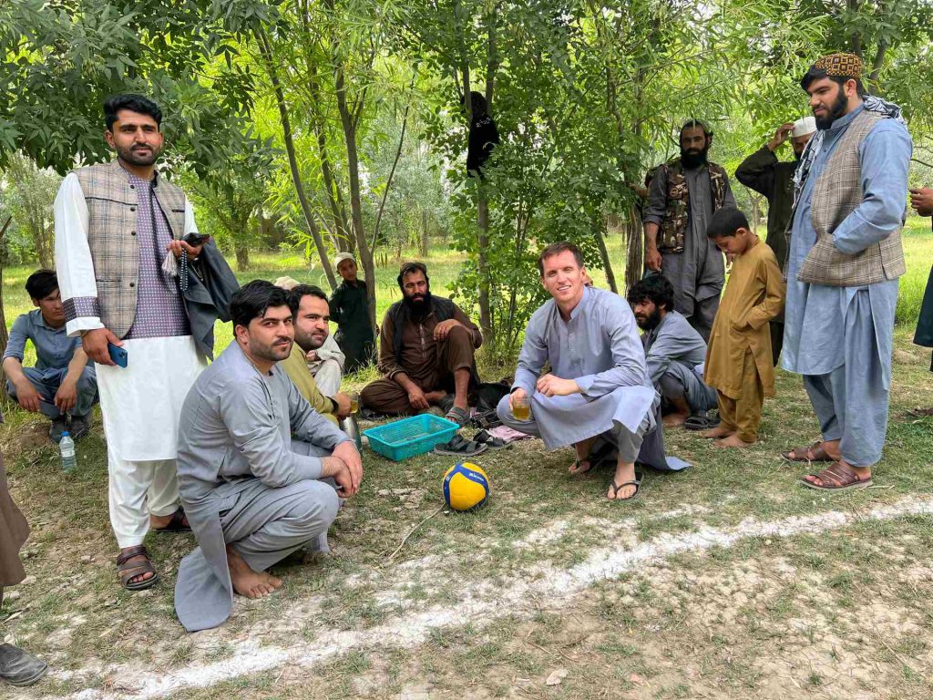 David Simpson and local people resting under the shade in Mazar, Afghanistan. Playing volley ball with the Taliban