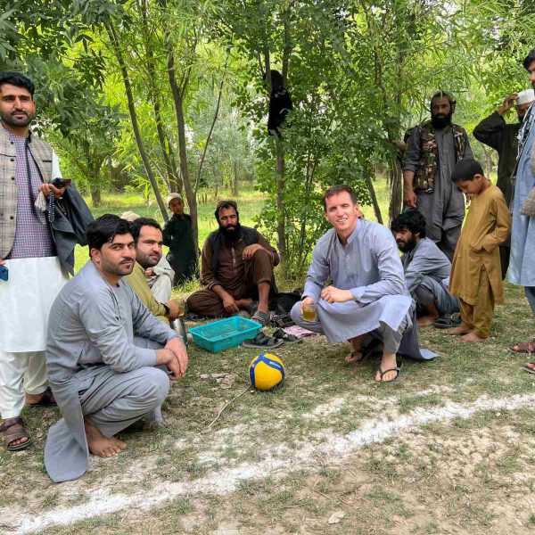 David Simpson and local people resting under the shade in Mazar, Afghanistan. Playing volley ball with the Taliban