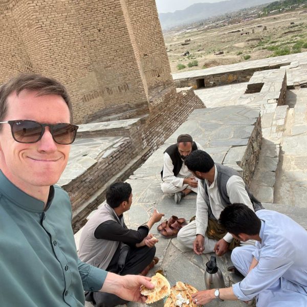 David Simpson and local people eating bread in Ghazi, Afghanistan. Sandstorm, bricks & cramps; Kabul to Kandahar