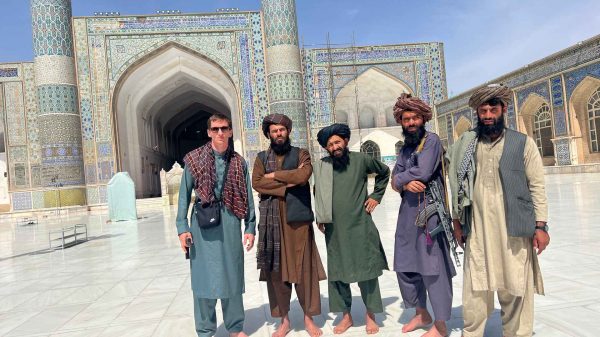 David Simpson with local people standing infront of the mosque in Herat, Afghanistan. Camels, rolling & sleep ‘n fly